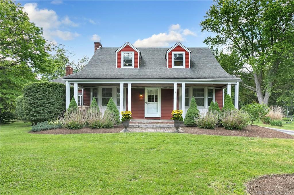 Beautiful red house with front porch on a green lawn